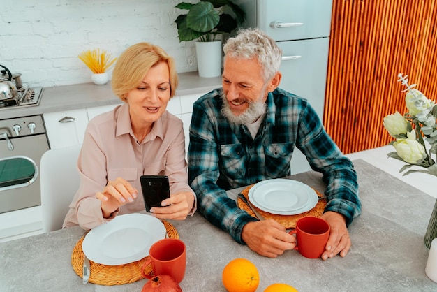Koppel ontbijt thuis en leest iets van smartphone