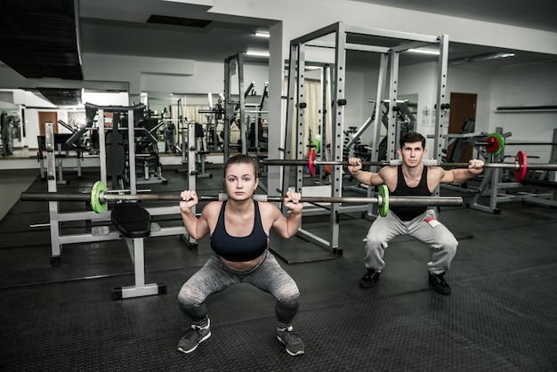 Koppel trainingsinstructeur met vrouw, beide met halters