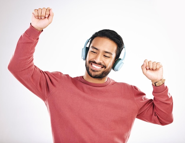 Koptelefoon blij en man dansen in een studio op muziek afspeellijst of album voor entertainment Geluksdans en Indiaas mannelijk model dat naar de radio gaat of een nummer streamt tegen een witte achtergrond