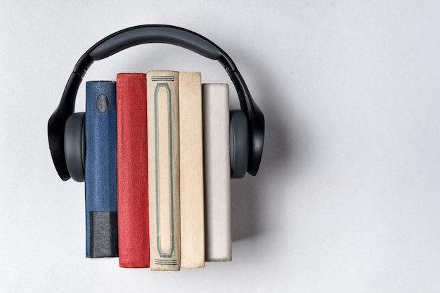 Koptelefoon gedragen op een stapel boeken tegen een witte achtergrond Literatuur in audioformaat Audioboek concept