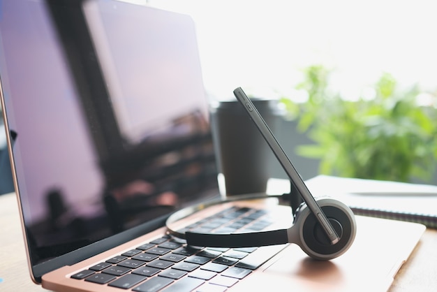 Koptelefoon met microfoon liggend op laptop toetsenbord op desktop closeup