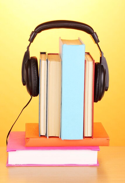 Foto koptelefoon op boeken op houten tafel op oranje achtergrond
