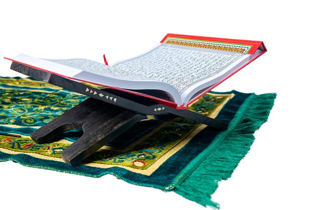 Koran geopend op een houten placemat in gebedskleed geïsoleerd op witte achtergrond