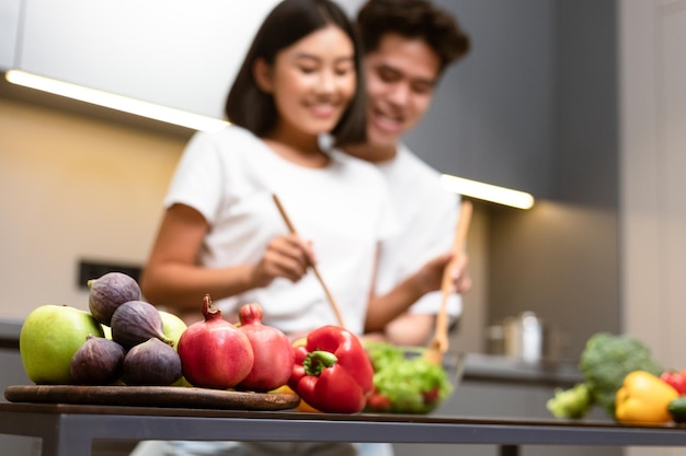 Koreaans familiepaar samen koken knuffelen staande in de keuken binnenshuis, focus op groenten. Voedsel bereiden in het weekend, gezonde voeding en maaltijden Recepten Concept. Ondiep