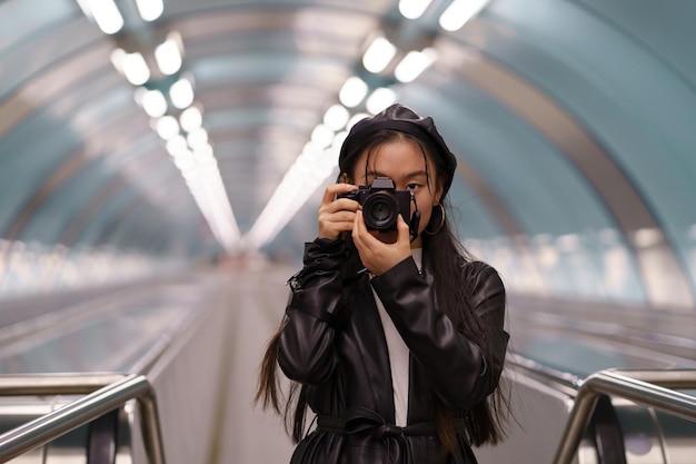 Koreaans toeristenmeisje maakt foto's op reis, jonge Chinese vrouw houdt camera vast op roltrap