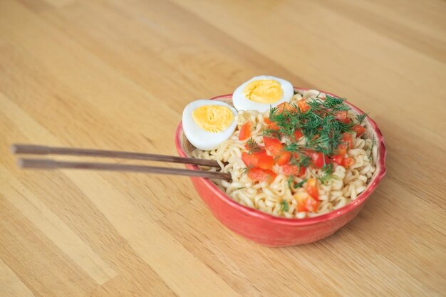 Koreaanse ramen noedels met groenten en ei met stokjes op houten achtergrond