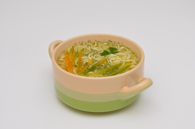 Koreaanse soep met noedels en groenten in een kom op een witte achtergrond