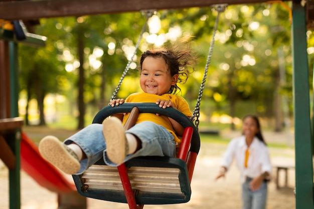 Korean baby girl swinging having fun with mommy on playground