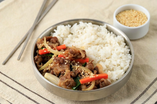 Foto bulgogi di manzo coreano con verdure fritte su riso bianco servito su una ciotola inossidabile