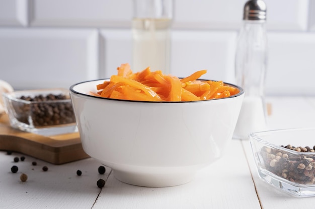 Korean carrot salad dressed with spicy sauce in a white salad bowl on a light background