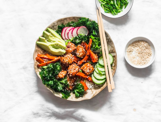 Korean chicken bowl with sweet potatoes rice kale and vegetables on a light background top view