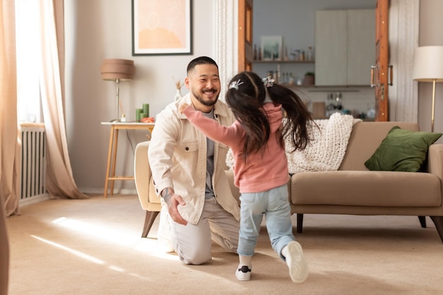 Photo korean daughter running towards her dad to embrace him indoor