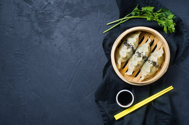 Korean dumplings in a traditional steamer, yellow chopsticks. 