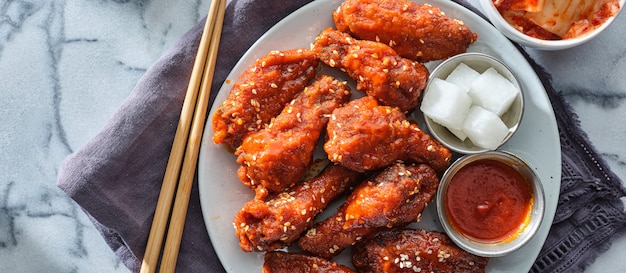 Korean fried chicken wings in gochujang sauce with pickled radish and kimchi wide composition