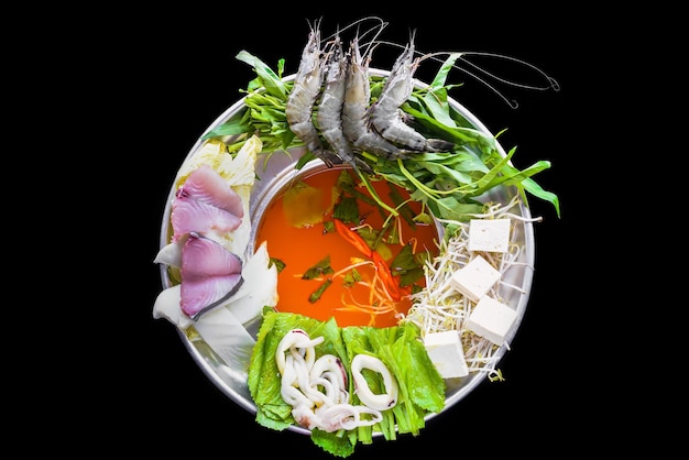 Korean hot pot with raw seafood on black background