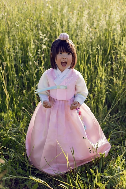 Korean national children pink costume on a four-year-old girl standing in a field with grass