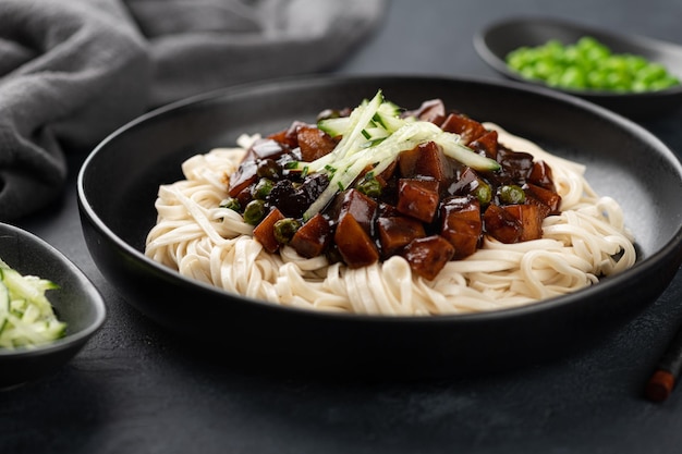 Tagliatelle coreane in salsa di fagioli neri su sfondo scuro fuoco selettivo