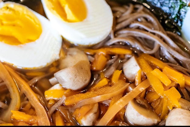 Korean noodles Ramyeon or Ramyun with spicy taste topped with egg yolk chili mushrooms egg yolk kimchi Presentation in Korean style