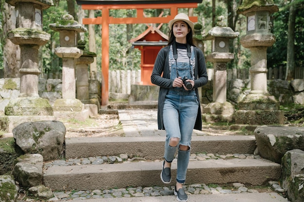 日本を旅行している韓国の写真家は、風光明媚なアトラクションを探しています。宗教遺産の背景にあるオレンジ色の鳥居と神社の美しさを楽しむアジア人観光客。