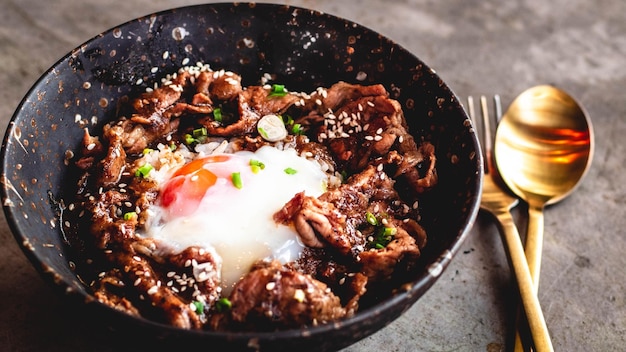 Korean Pork with egg on Rice in bowl ceramic plate with metal spoon and fork A traditional Korean tray meal food cuisine