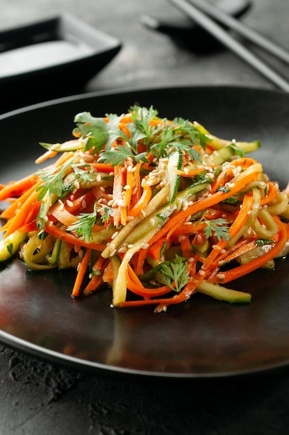 Korean salad with raw potatoes and vegetables In a black bowl Dark background Closeup