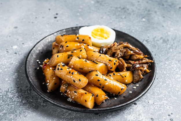 Корейский Tteokbokki Topokki жареный рисовый пирог в остром и остром соусе Серый фон Вид сверху