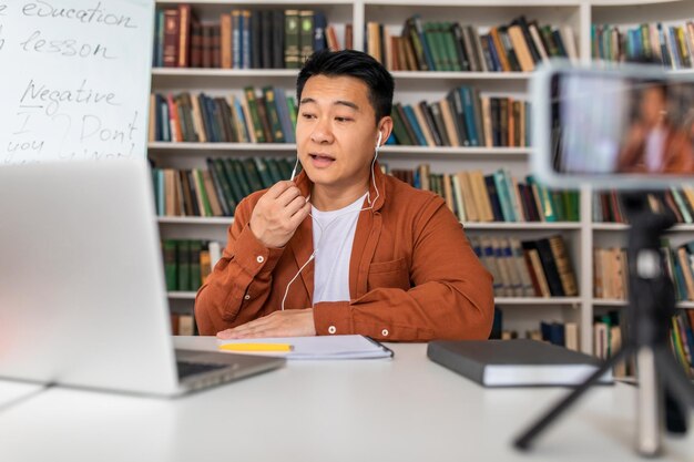 Korean tutor having online lecture talking to laptop at\
workplace