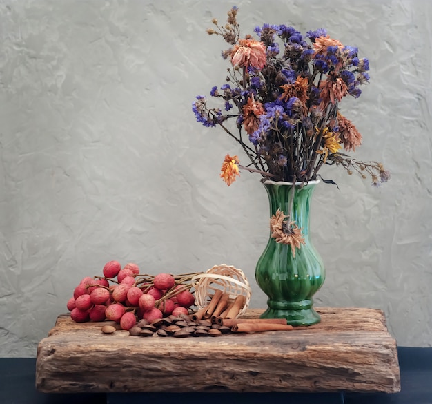 Korrel en gedroogde bloemen in groene vaas met stilleven