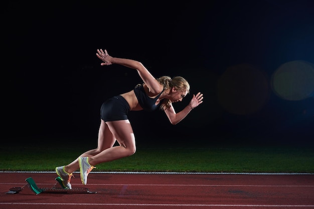 korrelig ontwerp van vrouwelijke sprinter die startblokken op de atletiekbaan verlaat. Zijaanzicht. exploderende start