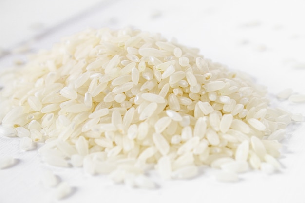 Korrels van ruwe witte rijst op een witte houten lijst van raad. Ingrediënten voor het koken.