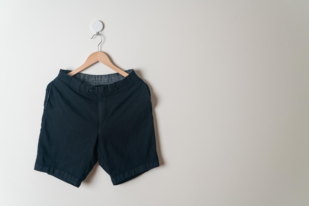 korte broek hangend met houten hanger aan de muur