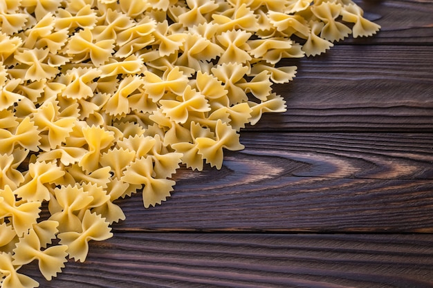 Korte pasta farfalle op donkere houten achtergrond. Rauwe gele macaroni. Italiaanse keuken. Kopieer ruimte.