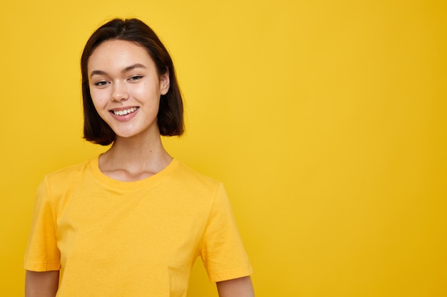 Kortharige brunette in gele tshirt poseren mode gele achtergrond
