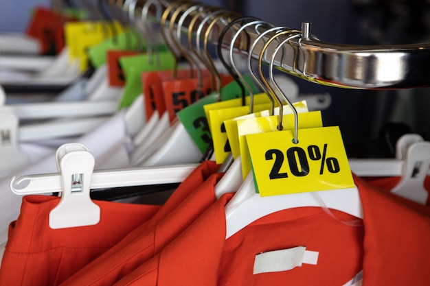 Foto korting verkoop tags, 20, 30, 50% korting, op hangers met kleding in casual kledingwinkel. modeconcept, kortingsseizoen, zwarte vrijdag, offline winkelen, gimmicks, vakantieverkoop.