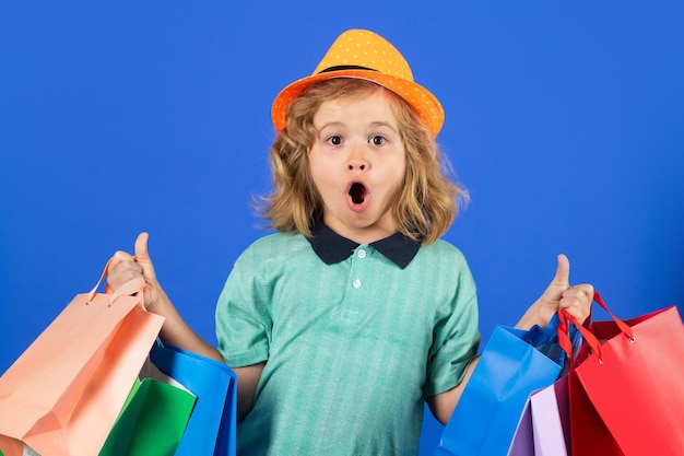 Foto kortingen en verkopen gelukkig kind met boodschappentassen kid met boodschappentassen die zich voordeed op blauwe studio
