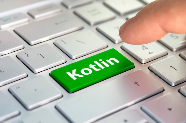 Kotlin computer language writing on button modern of gray\
laptop finger presses the button programmer for work