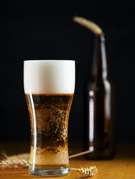 Foto koud licht bierpils in een glas op een donkere tafel close-up