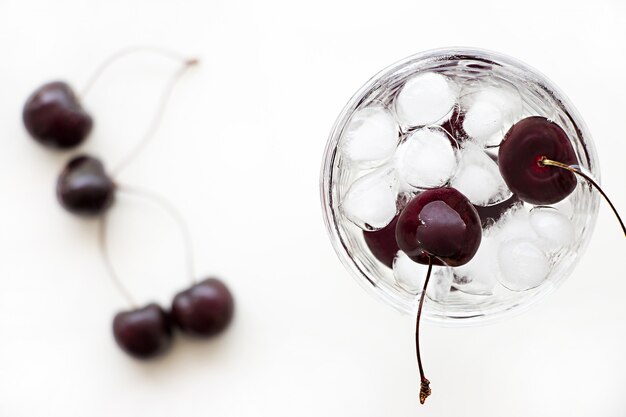 Koud verfrissend detoxwater met kers en ijsblokje in glas.