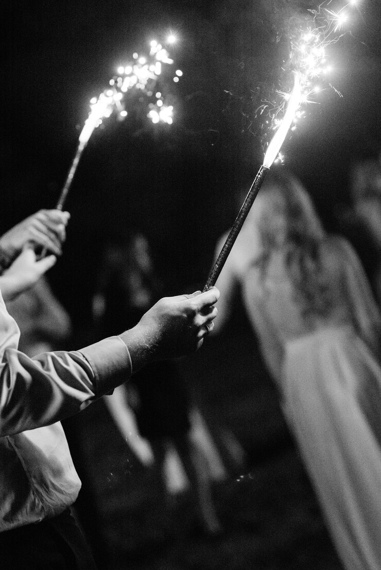 Koud vuur van taartkaarsen en vuurwerk in de handen van mensen rond de pasgetrouwden