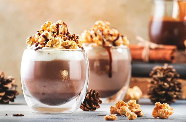 Koud winterchocoladedessert met slagroompopcorn en karameltopping in glazen op beige achtergrondplaats voor tekst