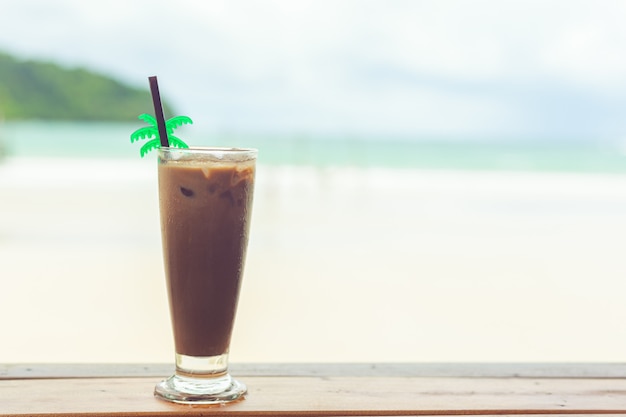 Koude cacao in een glas op een houten tafel aan zee in de zomer