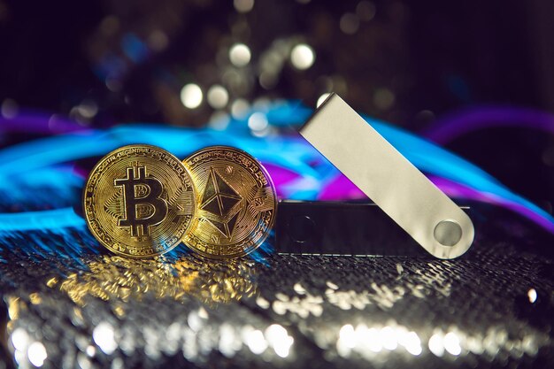 koude cryptocurrency-portemonnee en een gouden bitcoin en etherische munt op een zilveren glanzende achtergrond