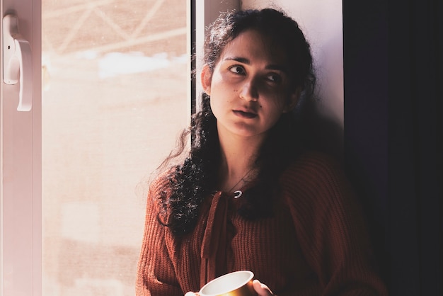 Koude herfstdagen een jonge multiraciale vrouw drinkt koffie in een gezellige vensterbank in het Midden-Oosten of mix...