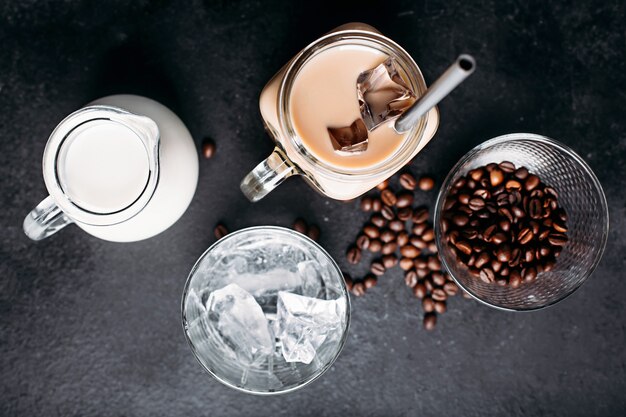 Koude ijskoffie met ingrediënten: ijsblokjes, melk, koffiebonen