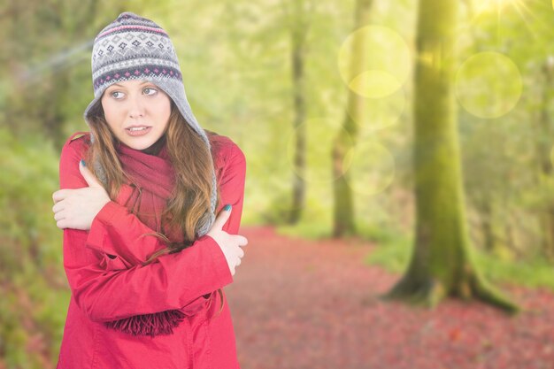 Koude roodharige met jas en hoed tegen een vredig herfsttafereel in het bos