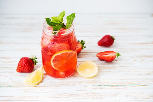 Koude zomeraardbeienlimonade in een pot op een witte achtergrond, selectieve focus, kopieerruimte