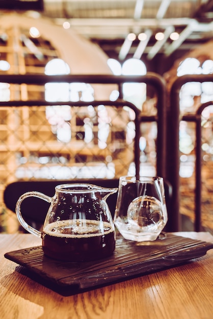 Koude zwarte koffiekruik met glas en ijs in coffeeshop