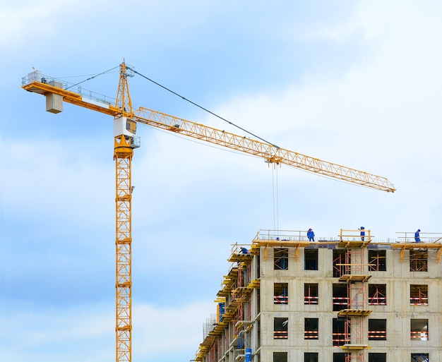 Kraan en arbeiders bij de bouw van woongebouw