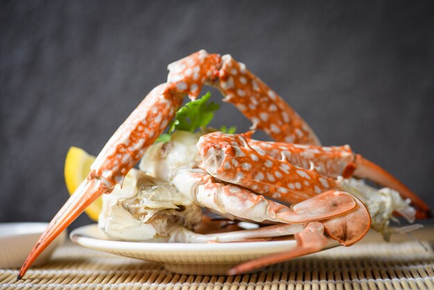 Krabvlees - gekookte krabklauwen en -benen op witte plaat en zeevruchtensaus op de lijst, blauwe zwemkrab