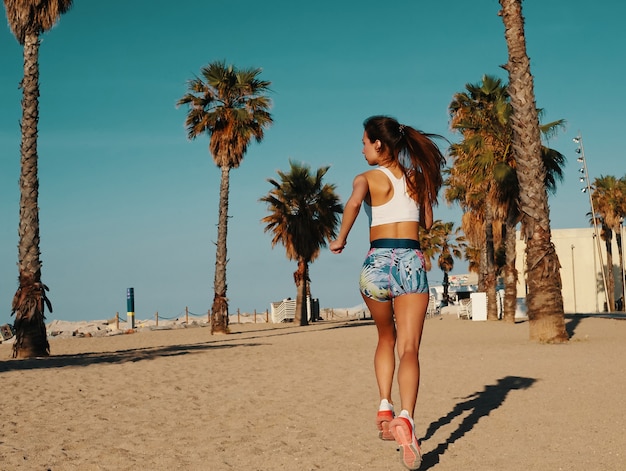 Kracht en balans. Achteraanzicht van mooie jonge vrouw in sportkleding joggen tijdens het sporten buitenshuis